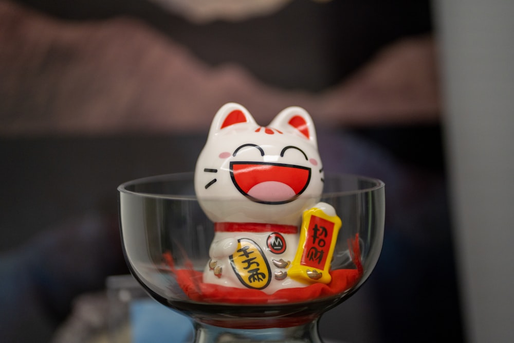 a cat figurine sitting in a glass bowl