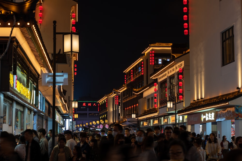 a crowd of people walking down a street at night