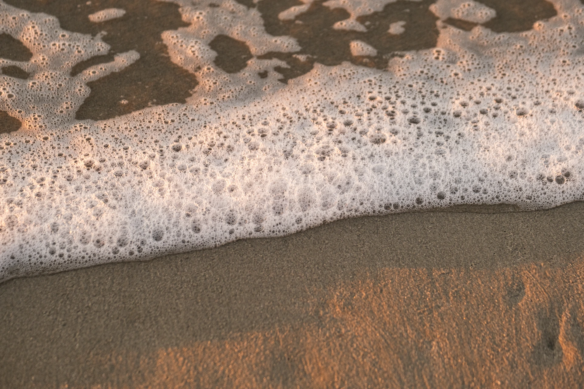 a close up of a wave on a sandy beach