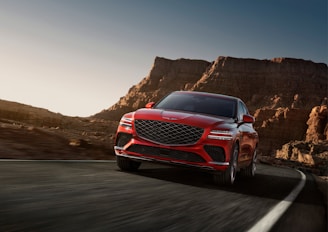 a red mercedes suv driving down a mountain road