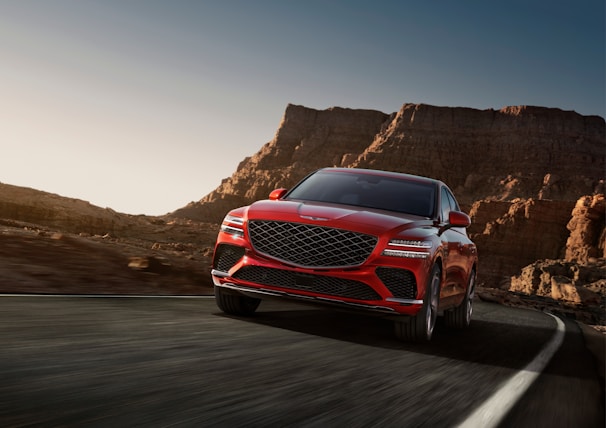 a red mercedes suv driving down a mountain road