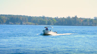 Close-up of a smiling member steering an electric boat, with the sea and coastline blurred in the background.