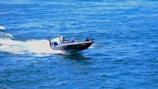 A sleek boat with a custom graphic wrap gliding on clear blue water.