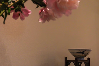 Close-up of delicate polymer clay flowers in soft blush pink and cream tones, arranged artfully on a wooden table.