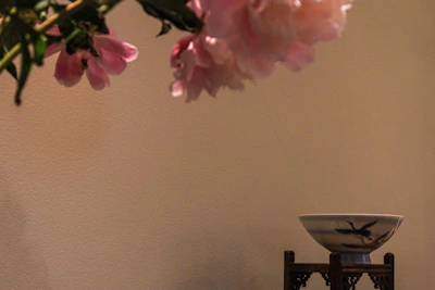 Close-up of delicate polymer clay flowers in soft blush pink and cream tones, arranged artfully on a wooden table.