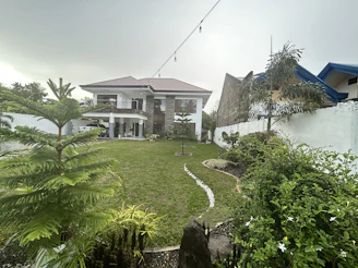 Modern two-story house with a well-kept garden under a clear sky.