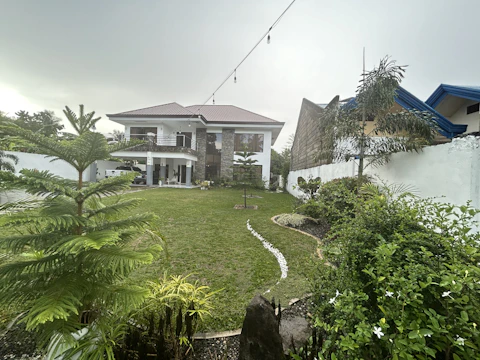 Modern two-story house with a well-kept garden under a clear sky.
