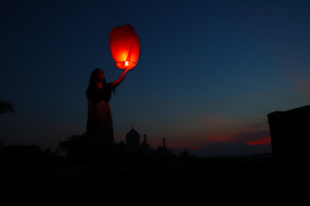 a woman holding a red lantern in the dark