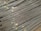 A large stack of steel rebar rods is neatly arranged, with labels and wires securing them at intervals. The rods have a ribbed texture and are uniformly aligned, extending diagonally from one corner of the image to the other.