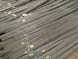 A large stack of steel rebar rods is neatly arranged, with labels and wires securing them at intervals. The rods have a ribbed texture and are uniformly aligned, extending diagonally from one corner of the image to the other.