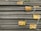 A stack of steel rebars neatly arranged with yellow labels attached to several bars. The labels contain various specifications and certifications. The rebars have a textured surface, indicating they are designed for reinforced concrete use.
