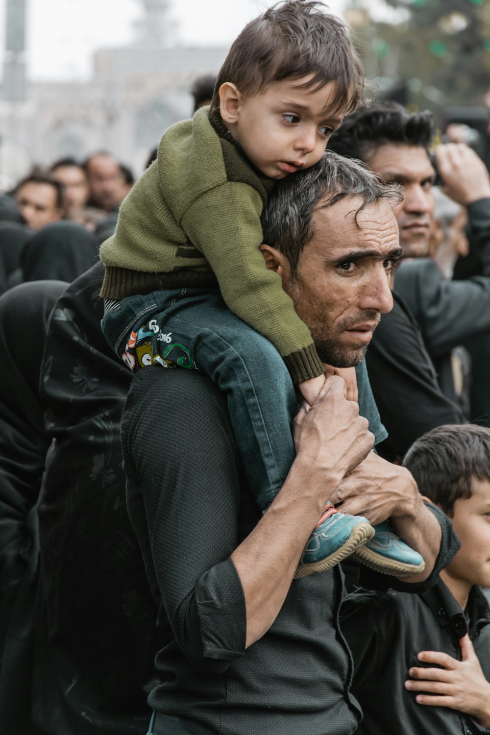 a man carrying a child on his shoulders