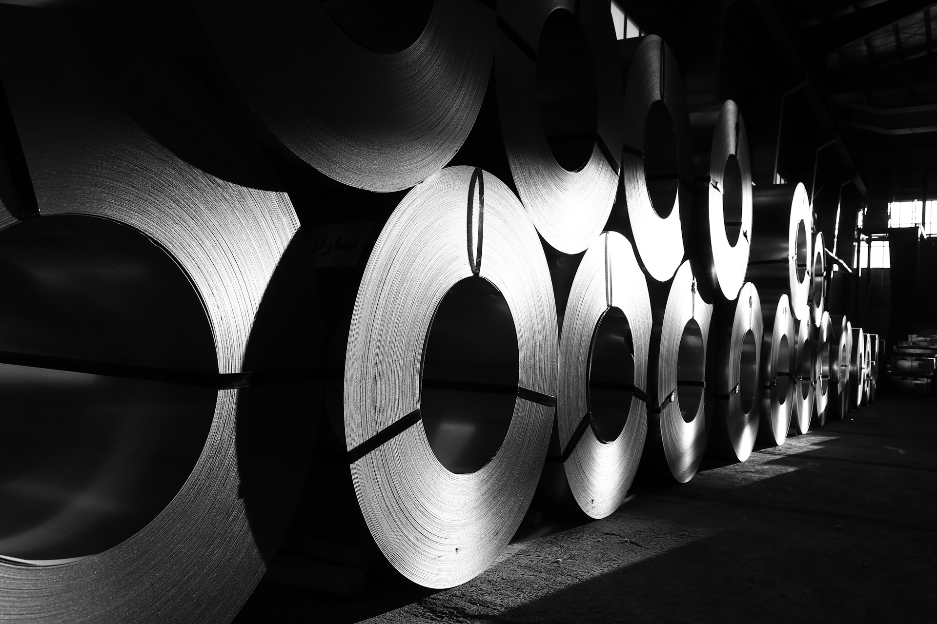 rolls of steel are lined up in a warehouse