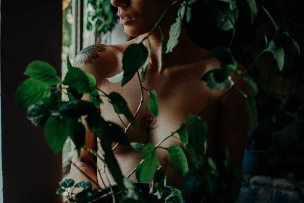 a shirtless man standing in front of a window