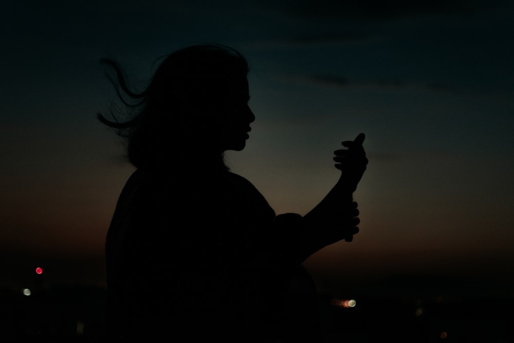 a silhouette of a person holding a cell phone