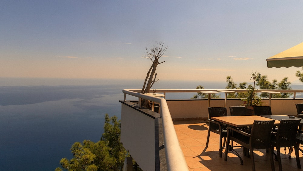 a table and chairs on a balcony overlooking the ocean