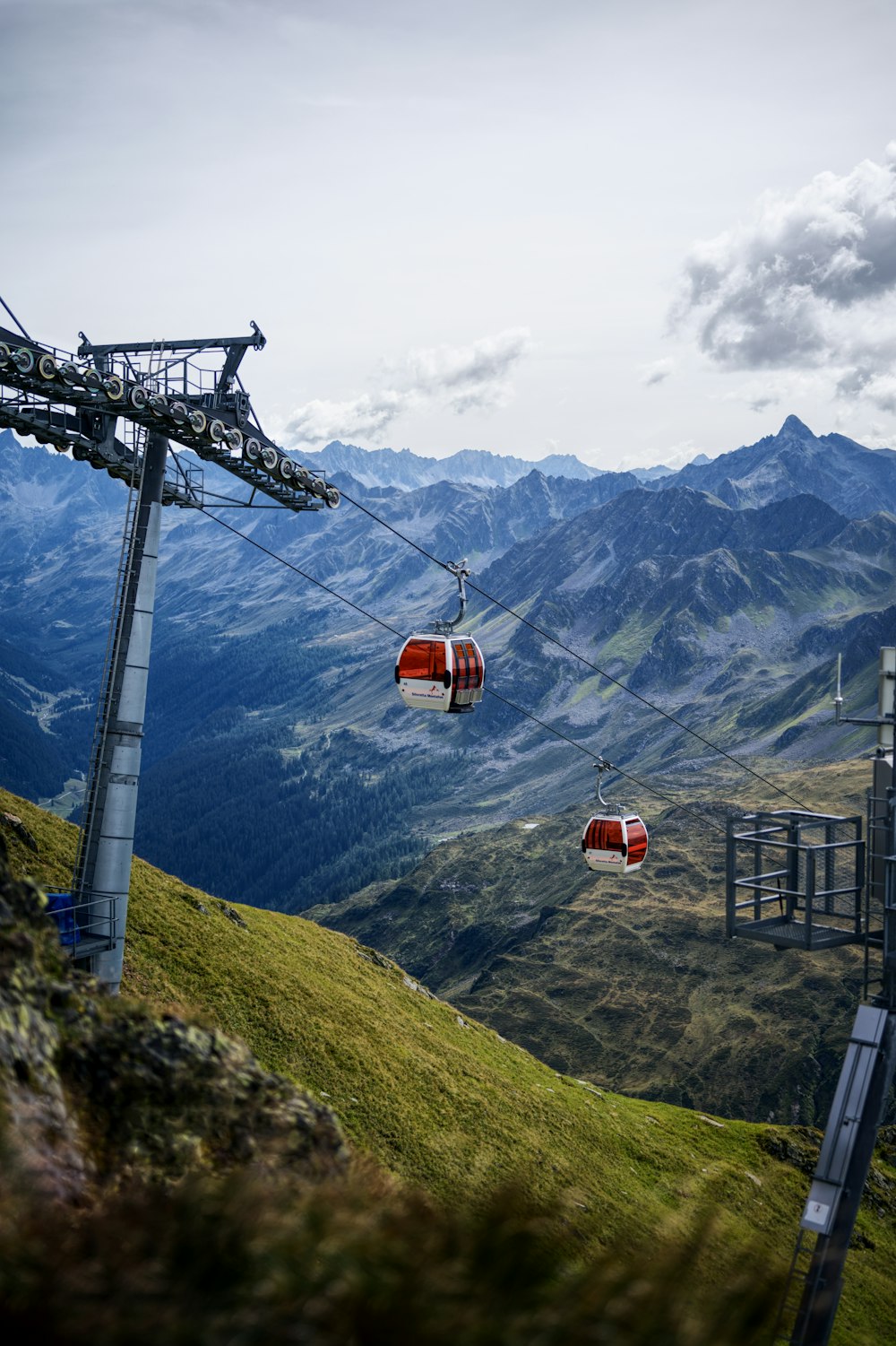 a couple of red chairs hanging from a wire above a mountain
