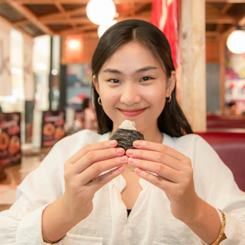 Close-up of a classic onigiri wrapped in crisp nori on a wooden plate.