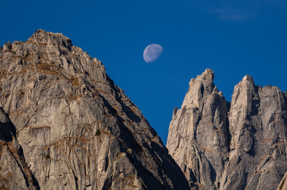 a full moon is seen above a mountain range