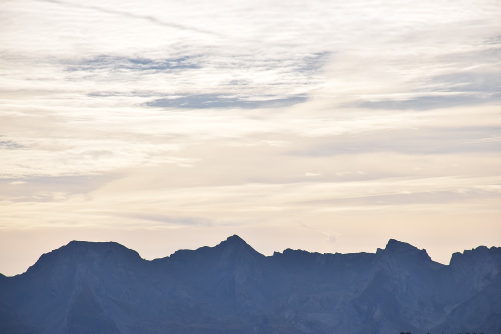 a mountain range with a few clouds in the sky