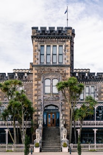 Historic mansion entrance with detailed stonework and palm trees.