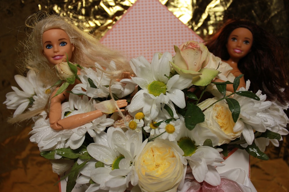 a doll and a bouquet of flowers on a table