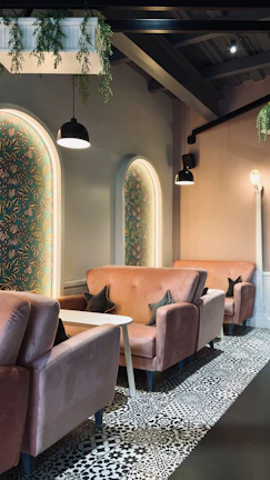 A cozy lounge corner bathed in soft rose gold lighting with plush seating.