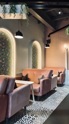 Stylish corner of the venue with plush seating, soft pink walls, and golden accents