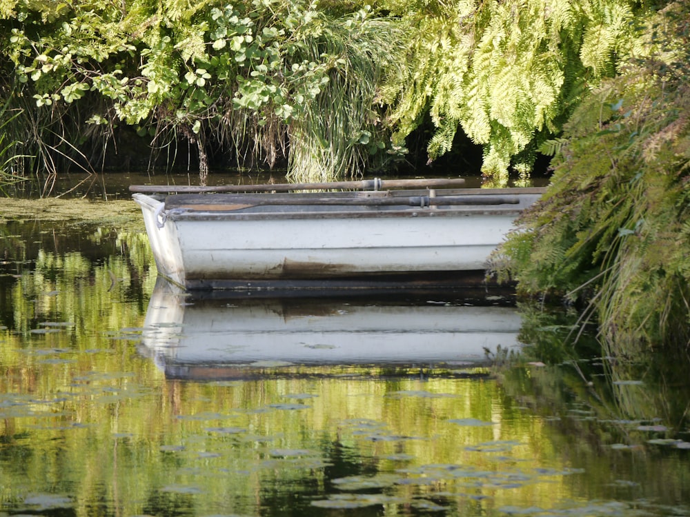 a small white boat floating on top of a lake