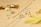 A collection of gold and silver jewelry is displayed on a light beige surface, including necklaces, rings, and earrings. A decorative gold bow and dried yellow flowers add a stylish touch to the arrangement, creating a luxurious and elegant aesthetic.