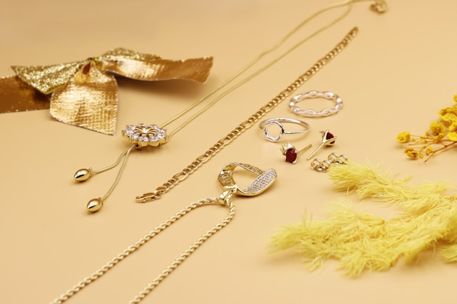 A warm maroon and cream-themed display of elegant bangles, rings, and hair accessories arranged artfully on a wooden table.