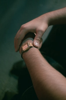 An elegant wrist adorned with a classic watch reflecting ambient golden light.