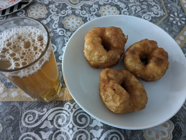 A plate of golden fried Oreos dusted with powdered sugar, sitting next to a vibrant drink.