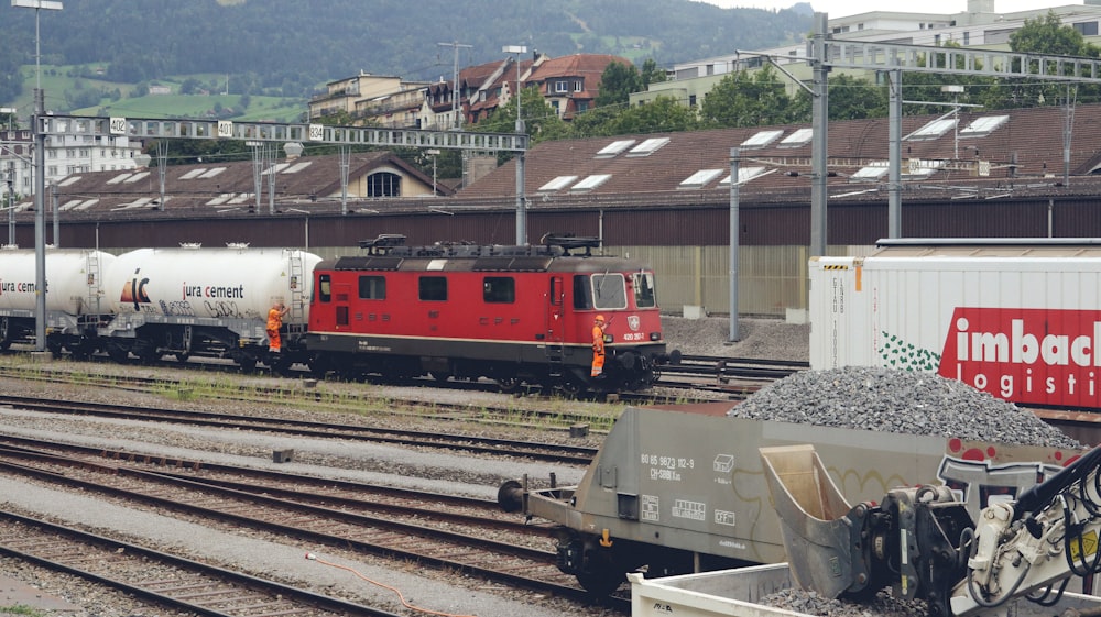 a red train traveling down train tracks next to a building