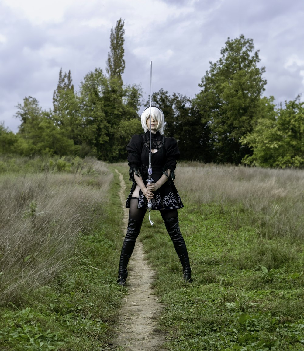 a woman with a sword standing in a field