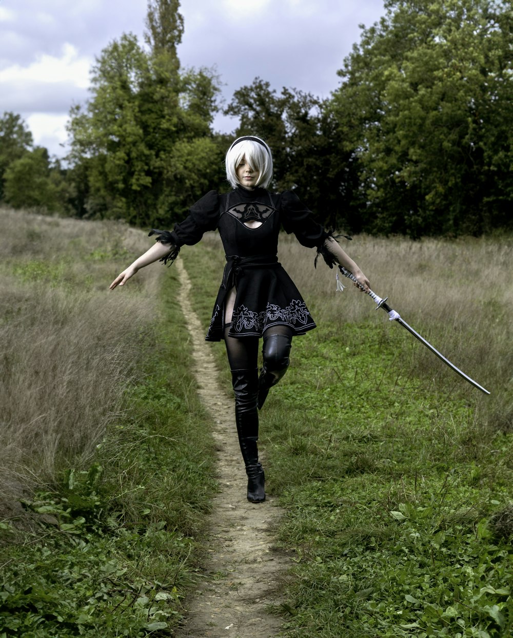 a woman in a black dress is walking down a path