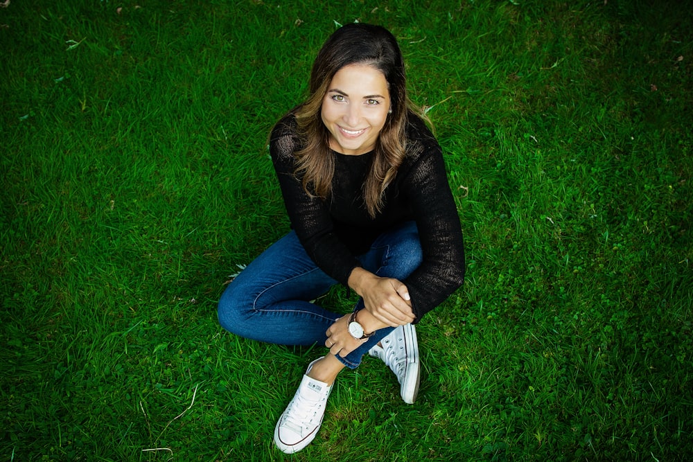 a woman sitting in the grass with her hands on her hips