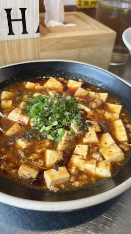Creamy palak tofu curry served in a rustic bowl with a sprinkle of spices.