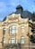 A historic building with an ornate architectural style. The structure features a mix of brick and stone with large windows and decorative elements near the roof. It has a prominent section labeled 'Biblioteca Universitară' and a dark slate roof with a small tower.