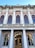 A neoclassical building facade with tall columns and ornate architectural details. The structure features multiple arched windows with decorative embellishments, such as sculpted figures and floral motifs. Above the entrance, the words 'Curtea de Apel Cluj' are inscribed. Two flags are displayed, one on each side of the building.