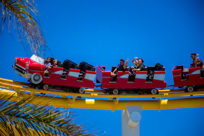 A joyful family smiling together in front of a colorful roller coaster on a sunny day.