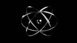 A metallic representation of an atom, with a central nucleus and orbiting paths for electrons, set against a black background.