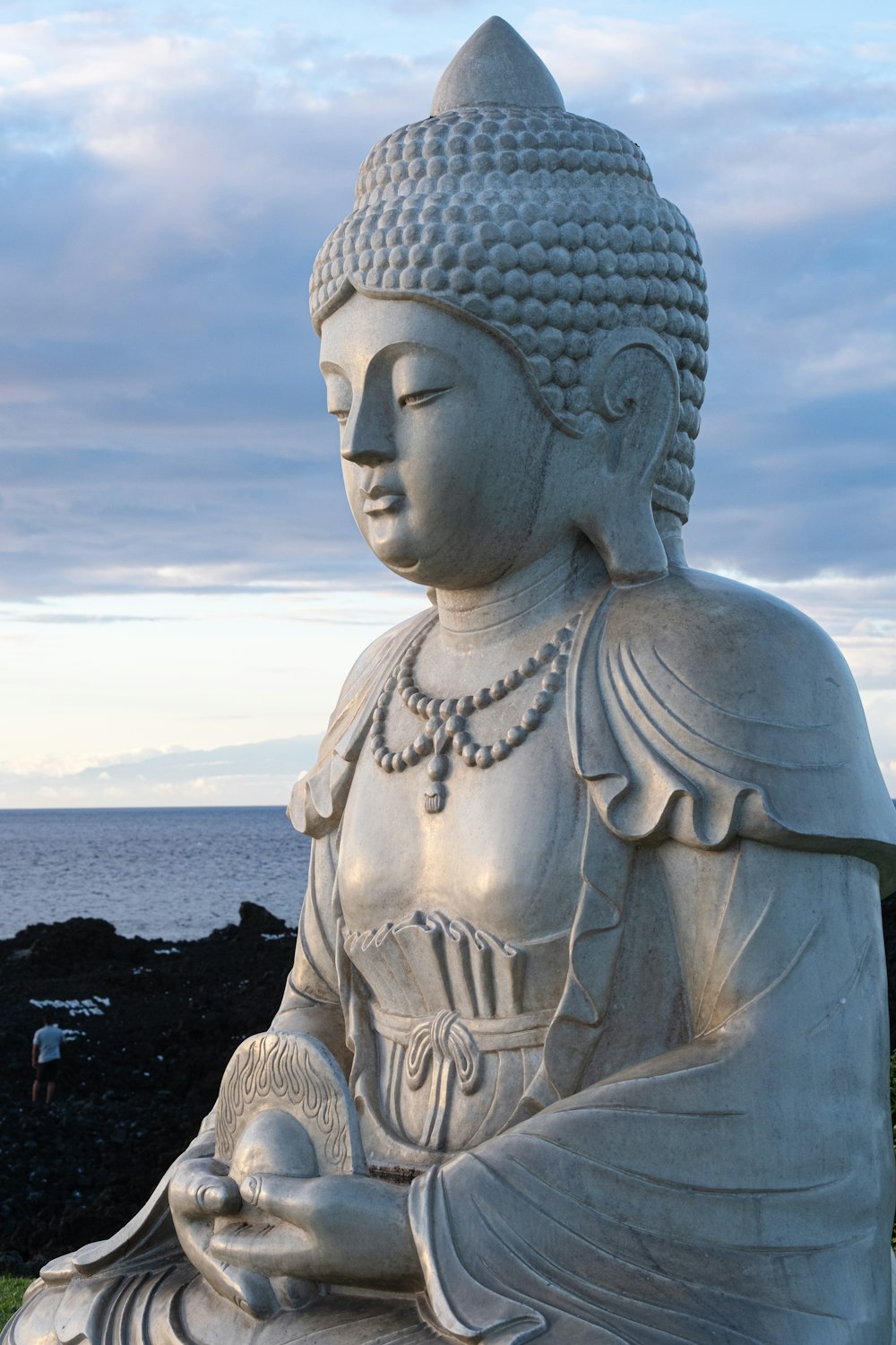 a buddha statue sitting on top of a lush green field