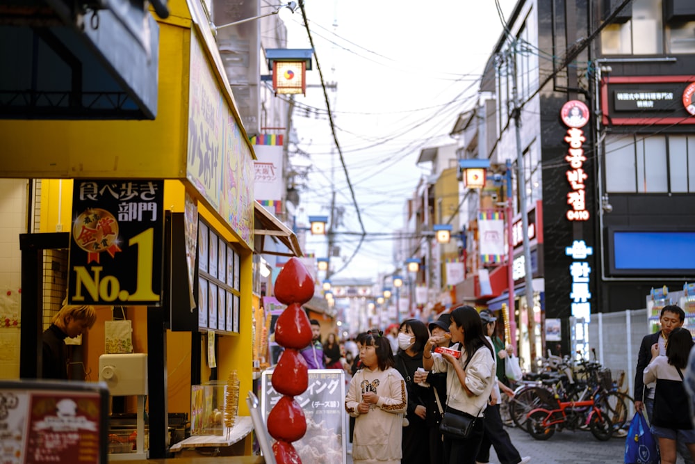 a group of people walking down a street next to tall buildings