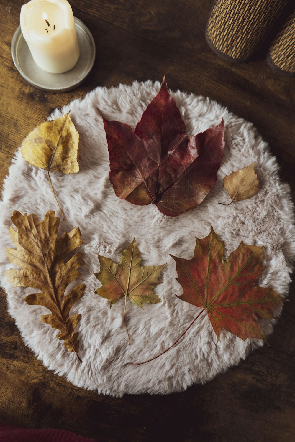 a white plate topped with leaves next to a candle