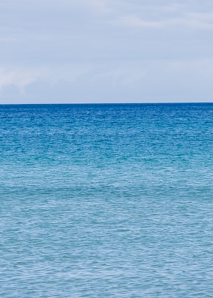 A tranquil seascape with sky blue and white tones in a wooden frame.