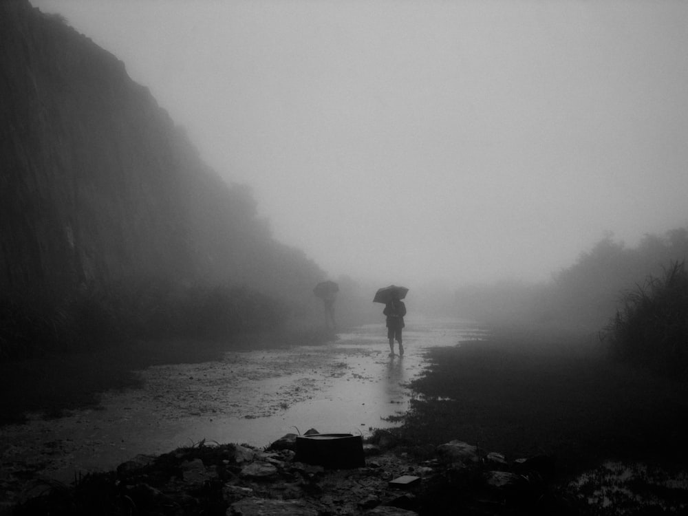 a couple of people walking down a wet road