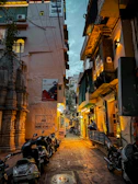 A cozy hostel courtyard with motorbikes lined up, surrounded by warm lighting at dusk