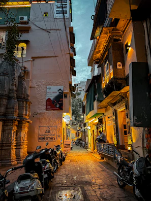 A cozy hostel courtyard with motorbikes lined up, surrounded by warm lighting at dusk