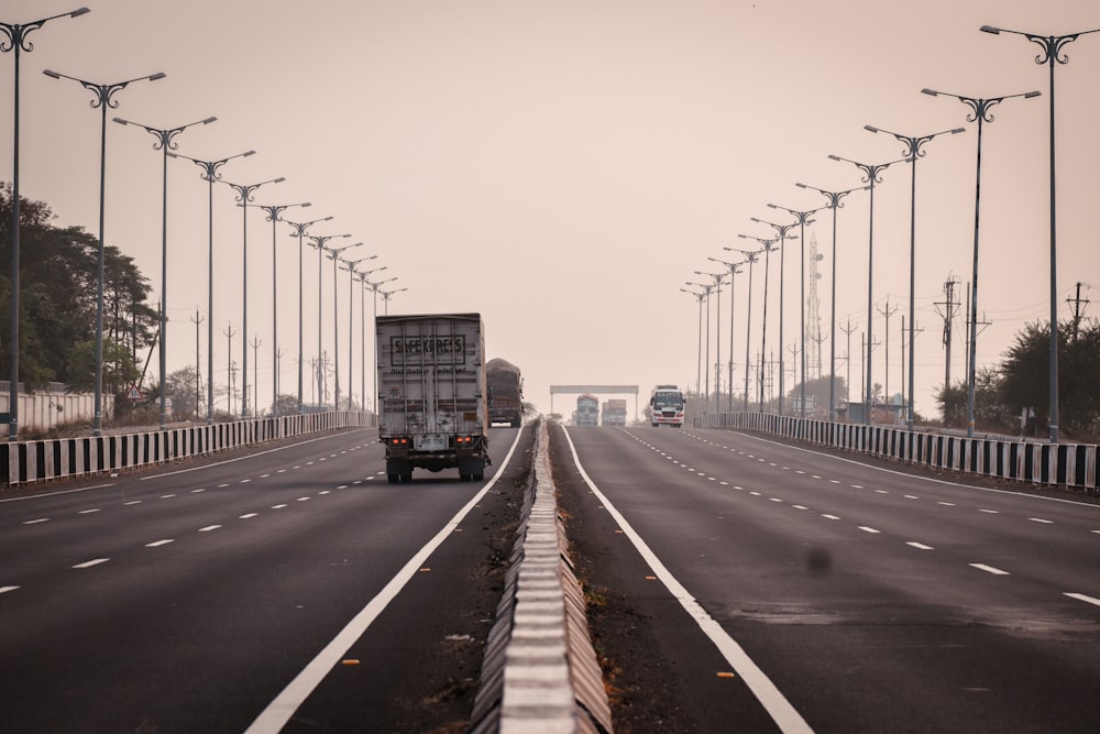 a truck driving down a highway next to a row of street lights